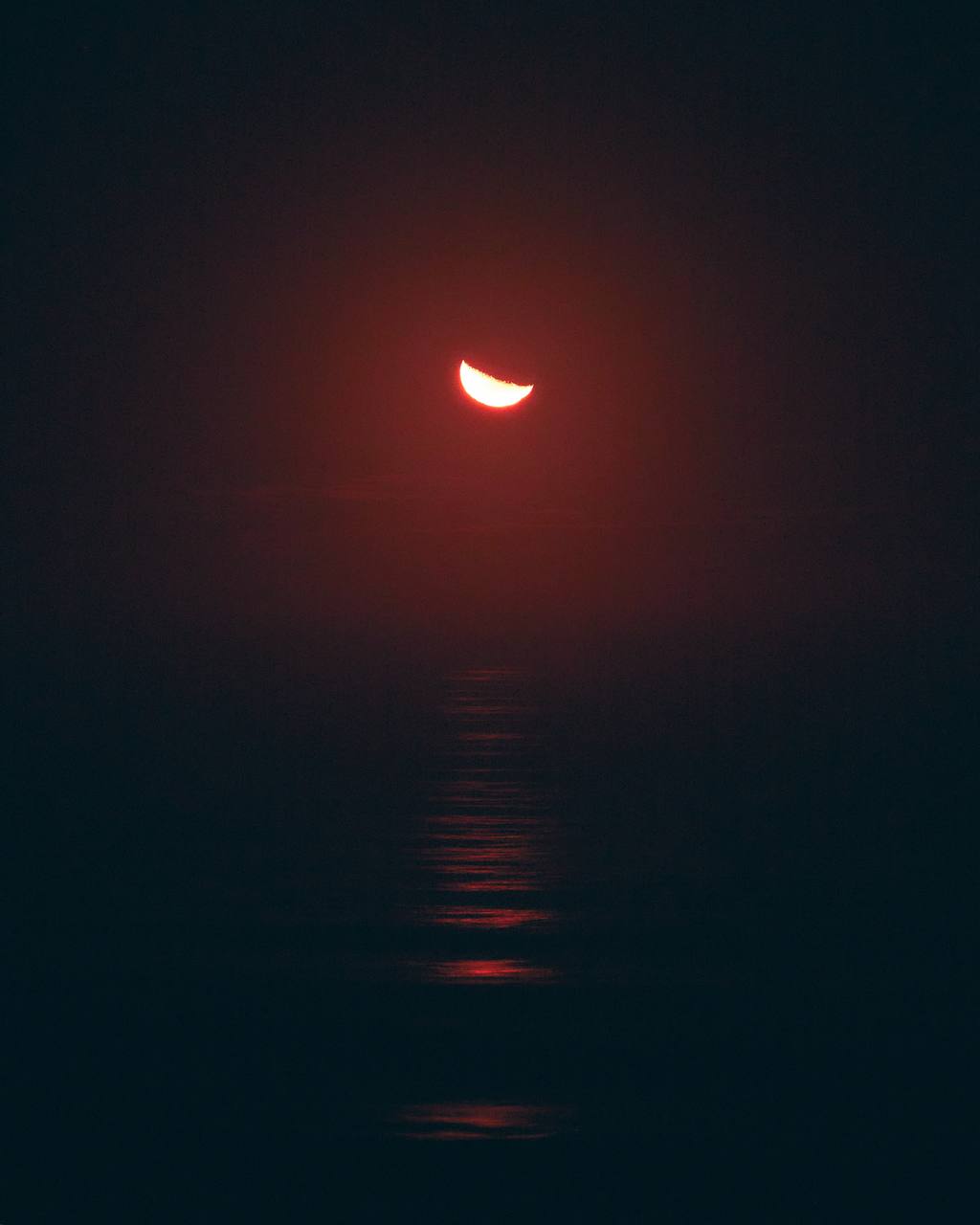 Luna creciente roja sobre el mar al amanecer